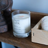 Candle labeled 'Tribe of Oak' on a wooden surface with decorative items.
