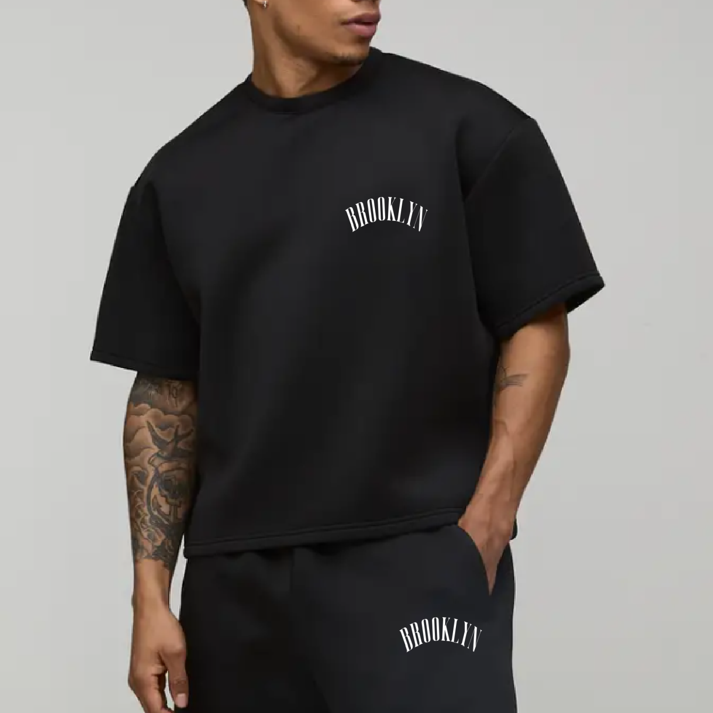 Person wearing a black 'Brooklyn' t-shirt and shorts on a gray background