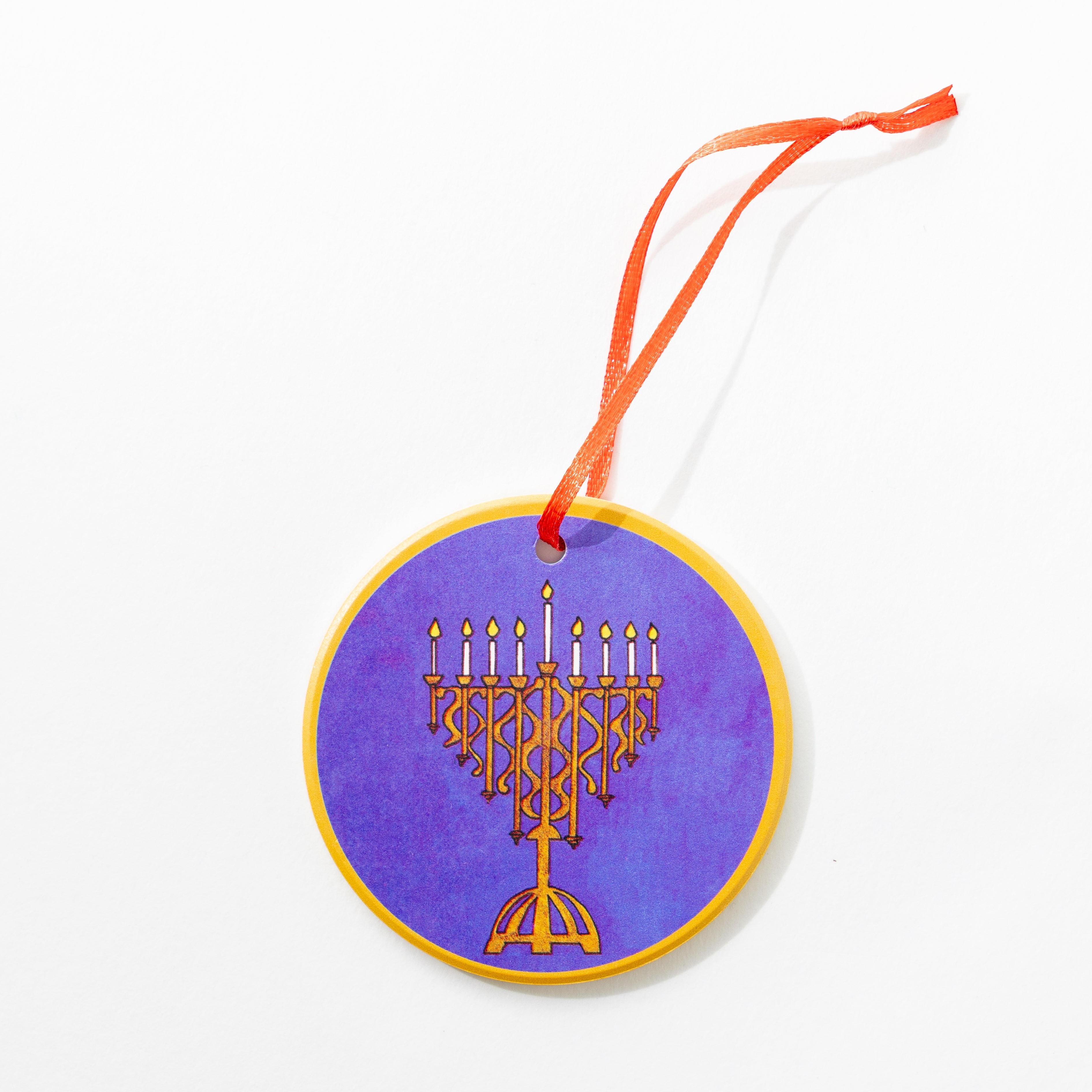 Melanie Hope Greenberg artist ceramic decorative ornament with a gold Menorah design on a purple background