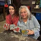 Two women holding mosaic art pieces in a casual setting