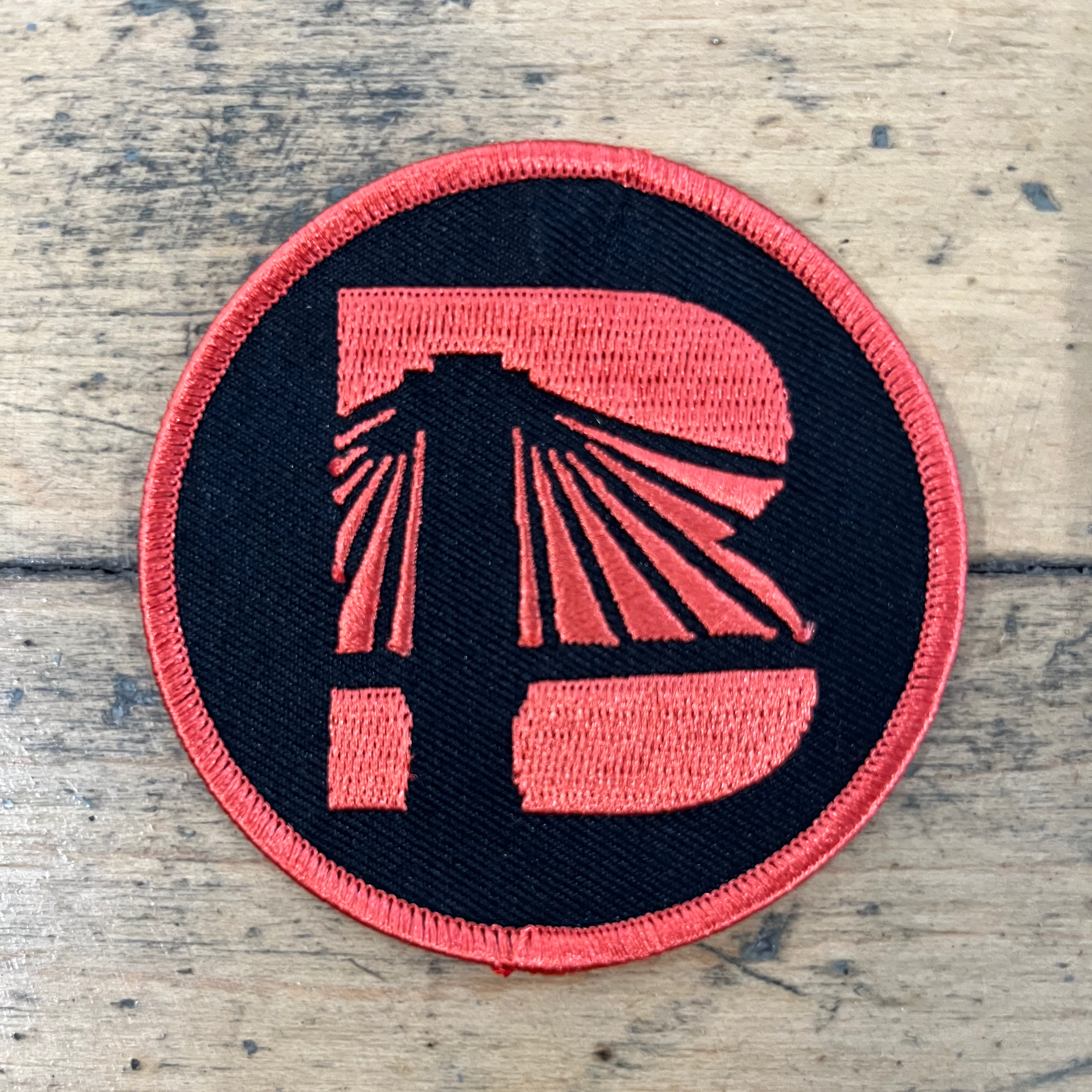 Circular patch with red and black design on a wooden surface