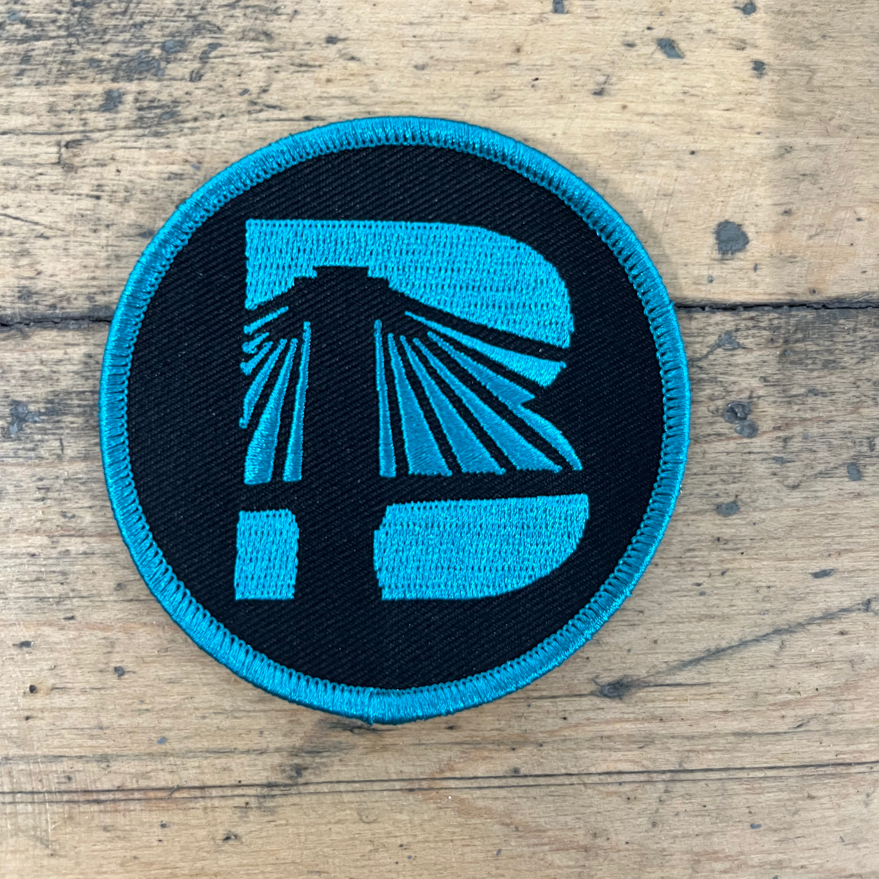 Round patch with blue and black design on a wooden surface