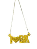 Gold necklace with a 'NYK' pendant on a dark wooden surface