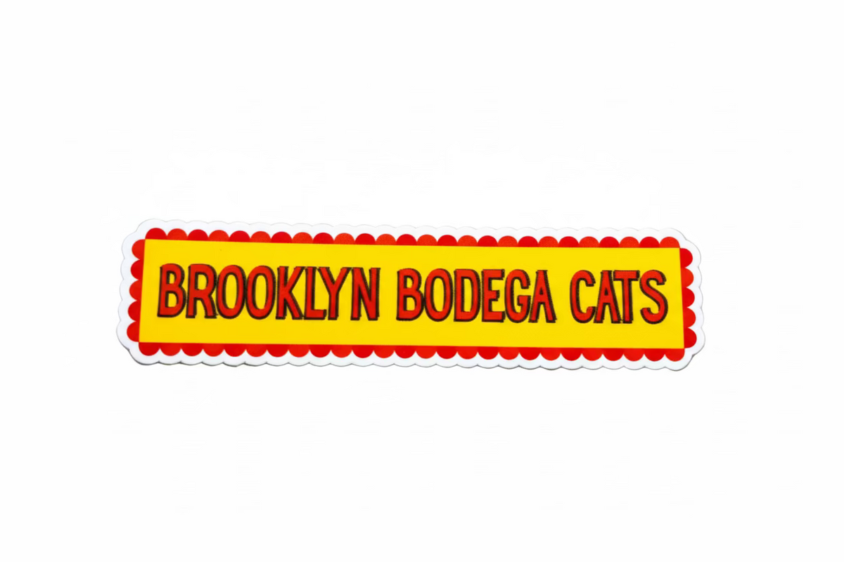 Sticker with 'Brooklyn Bodega Cats' text on a wooden surface