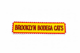 Sticker with 'Brooklyn Bodega Cats' text on a wooden surface