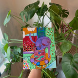 Colorful artwork held up in front of a plant