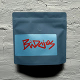Blue coffee bag with red text on a textured gray background