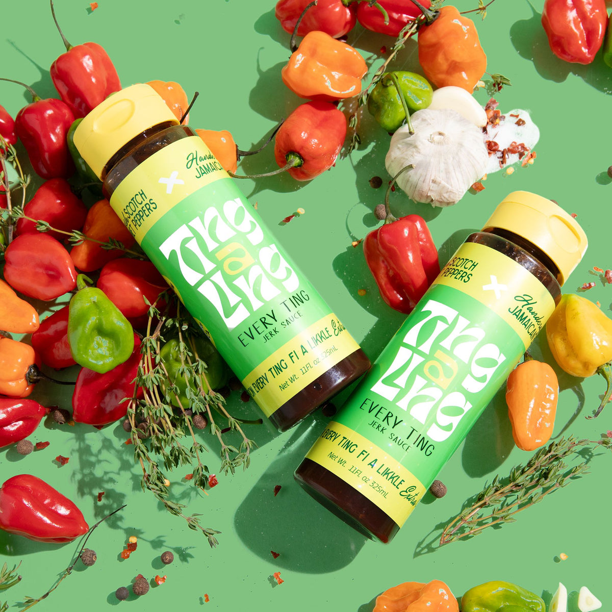 Jerk  hot sauce surrounded by peppers and herbs on a green background