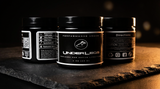 Three black jars of 'Underlegs' performance cream on a dark surface with a blurred background.