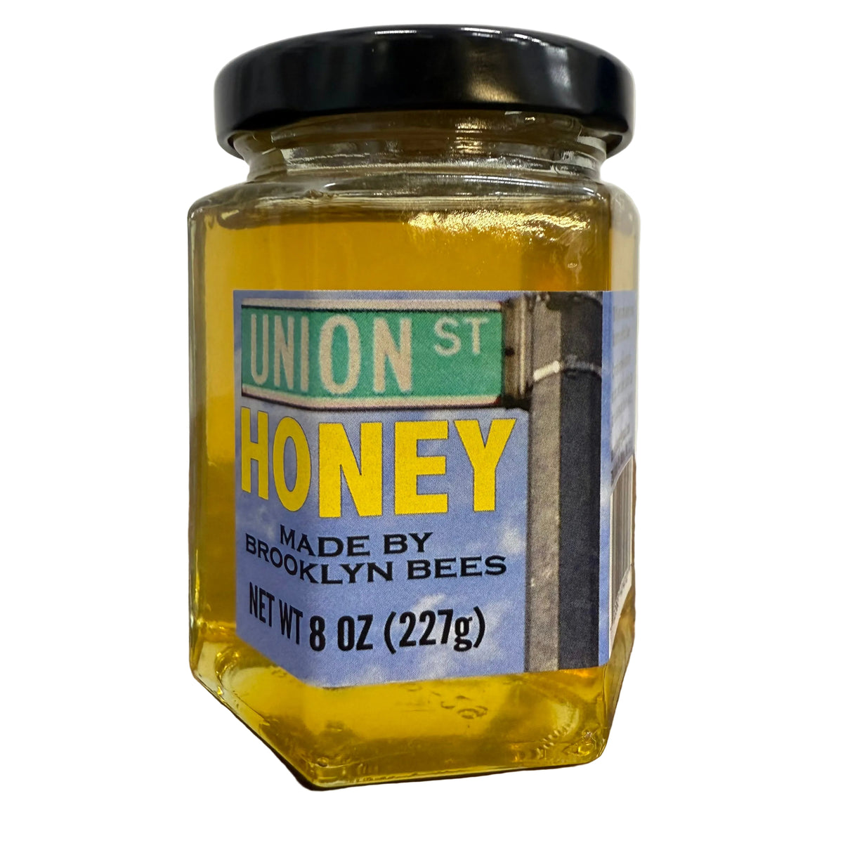 Jar of honey with a label reading 'Union St Honey Made by Brooklyn Bees' on a wooden surface.