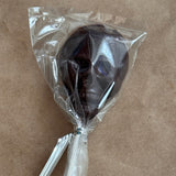 Chocolate lollipop in clear plastic wrap on a brown background